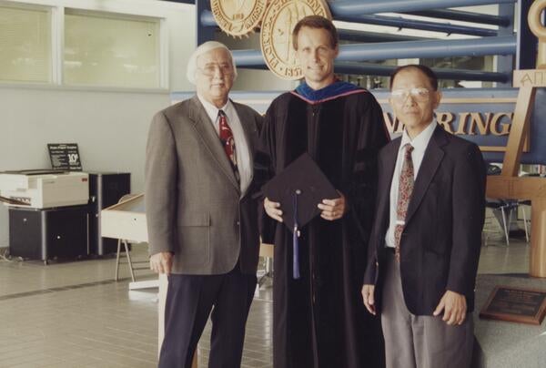 PhD Graduate, Geoffrey Brooks, in cap and gown with Dr. Fred Simons and Dean Ching Jen Chen