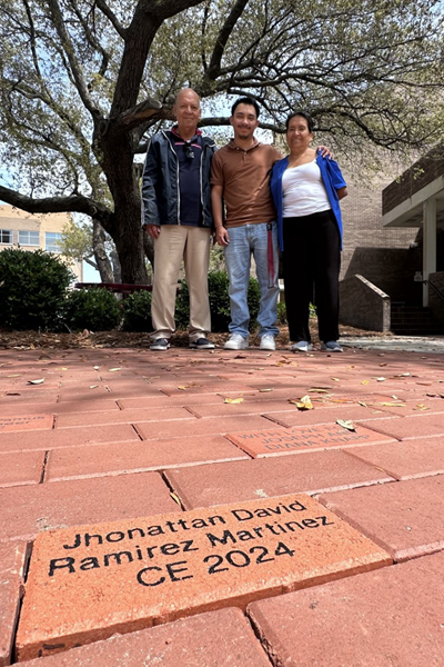 Jhonattan Ramirez places a legacy brick with his name on it in the walkway
