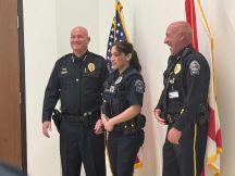 Joey'liz Cruz and other police officers stand beside U.S. and Florida state flags.