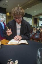 Student robed, then signs Freshmen Book