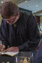 Student robed, then signs Freshmen Book