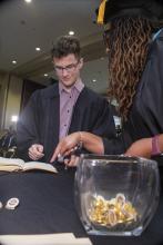 Student robed, then signs Freshmen Book