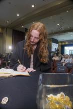 Student robed, then signs Freshmen Book