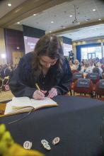 Student robed, then signs Freshmen Book