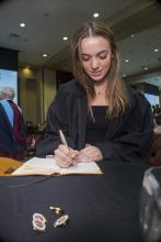 Student robed, then signs Freshmen Book
