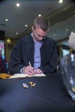Student robed, then signs Freshmen Book