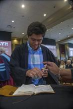 Student robed, then signs Freshmen Book