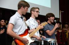 Incoming first-year Devin and Drew Guy with brother Luke, singing and performing the National Anthem
